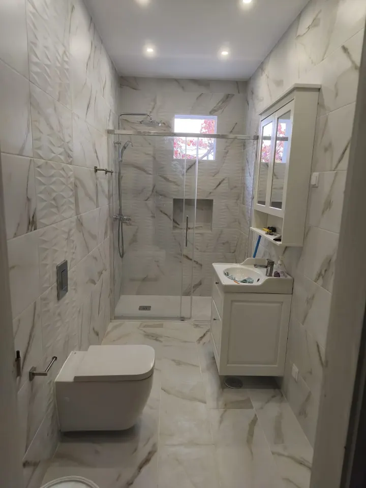 Casa de banho clara concluída, com revestimento de efeito mármore